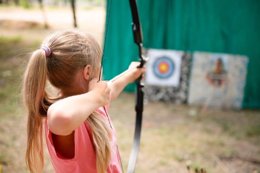 Female archer aiming with the bow at the target.